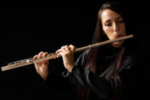 A beautiful woman playing the flute against a black background