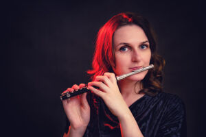 Woman playing the piccolo against a dark background