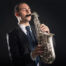 A man in a suit playing the saxophone with passion
