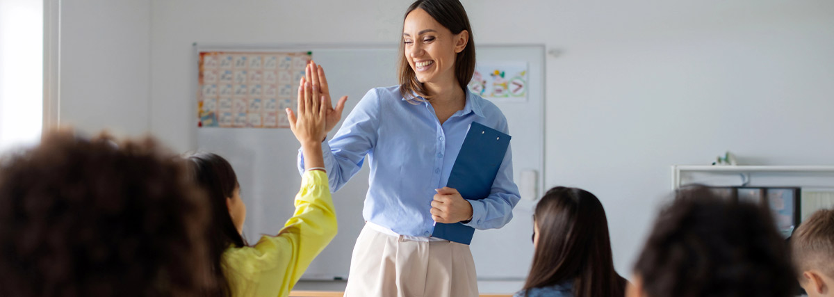A smiling teacher teaching their students in a classroom
