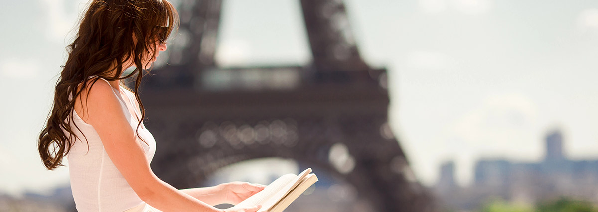 A young woman reading in front of the Eiffel Tower, a symbol of learning and inspiration