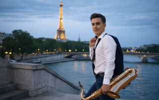 A man holding a saxophone outdoors with the Eiffel Tower in the background