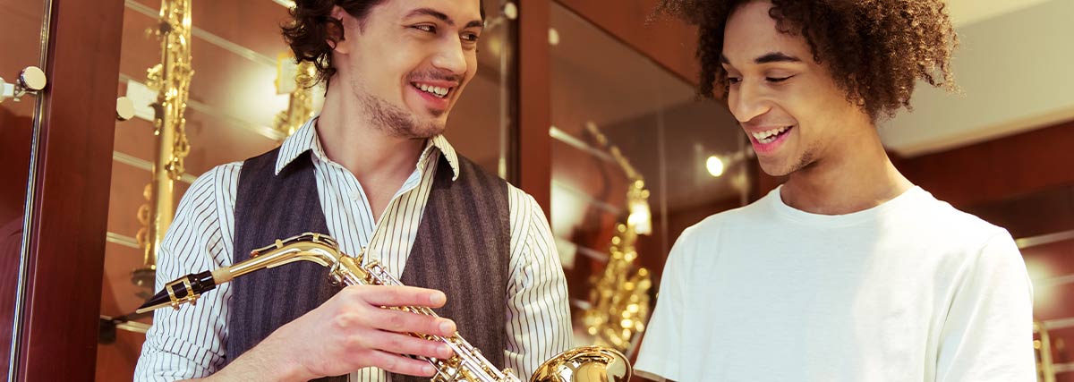 Un homme souriant présentant un saxophone à une autre personne