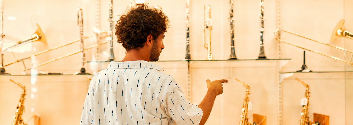 Vue de dos d’un homme montrant des saxophones du doigt