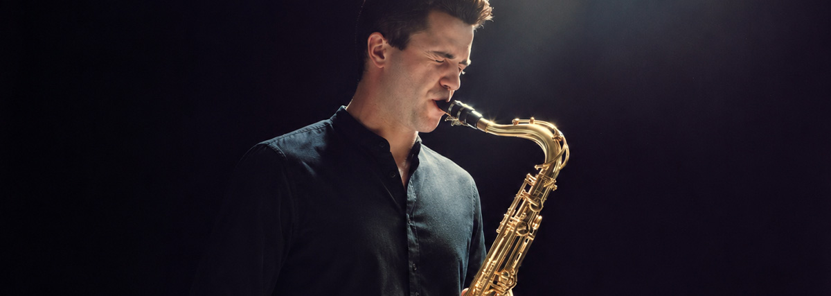 Adult saxophonist playing the tenor saxophone under stage lighting