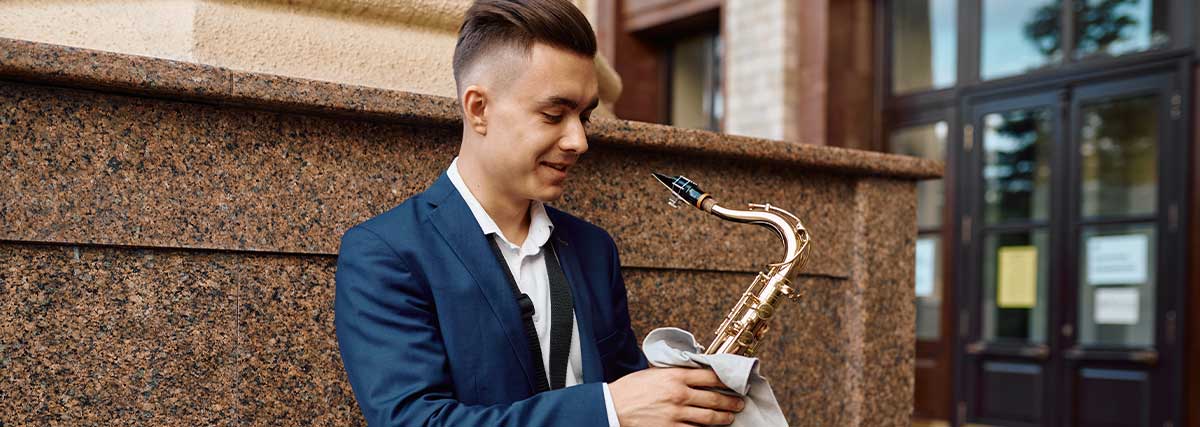Adult saxophonist cleaning his saxophone after a musical performance