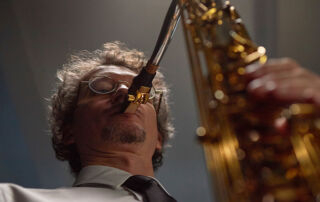 Professional saxophonist playing on stage with a close-up view of the instrument.