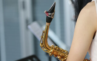 Élève saxophoniste tenant un saxophone alto, illustrant l’importance du bec et de l’anche