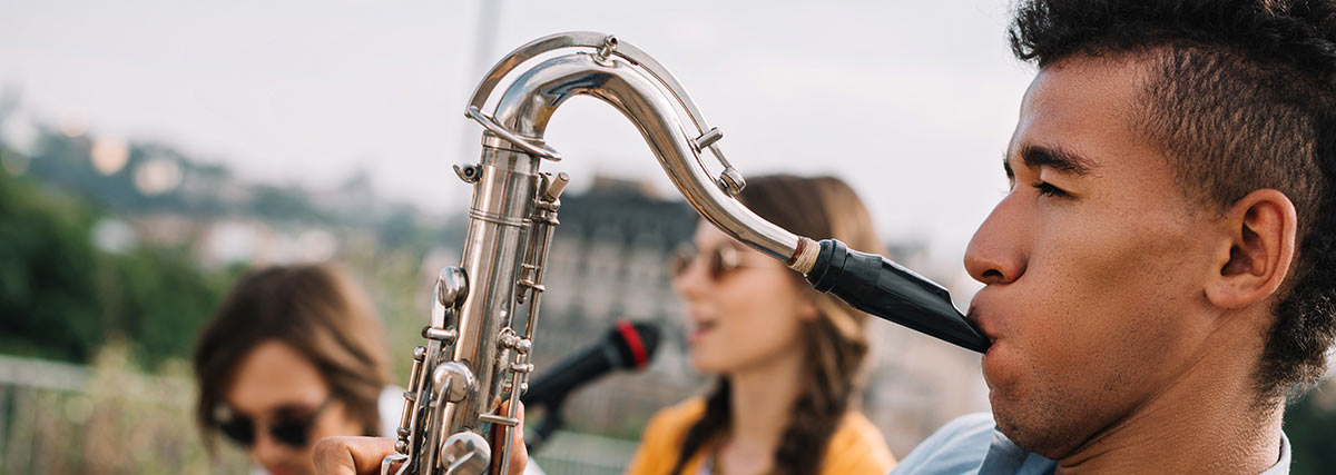 Saxophoniste se produisant en extérieur avec d’autres musiciens